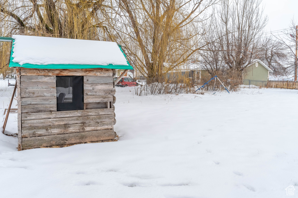 Yard layered in snow with an outbuilding, a storage shed, and fence
