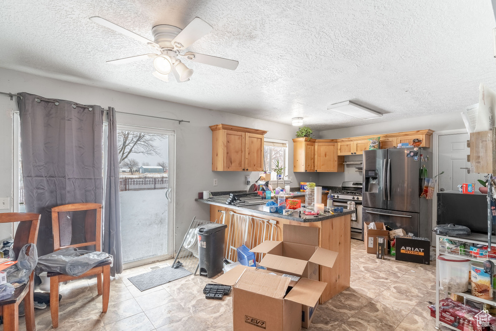 Kitchen featuring dark countertops, a textured ceiling, appliances with stainless steel finishes, and a ceiling fan