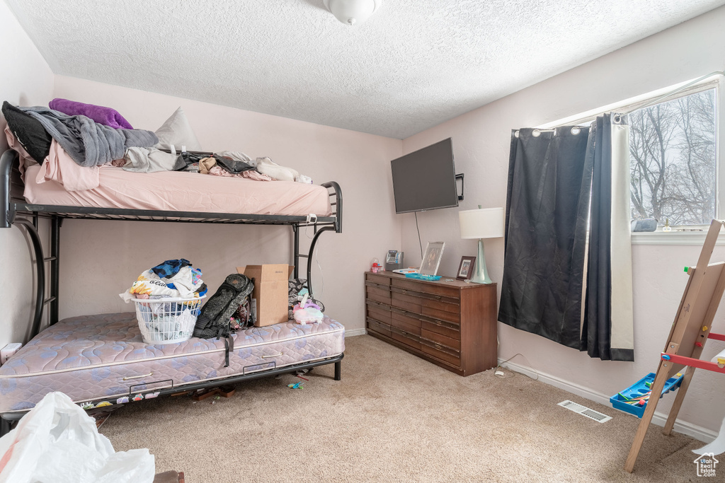 Carpeted bedroom featuring a textured ceiling, visible vents, and baseboards