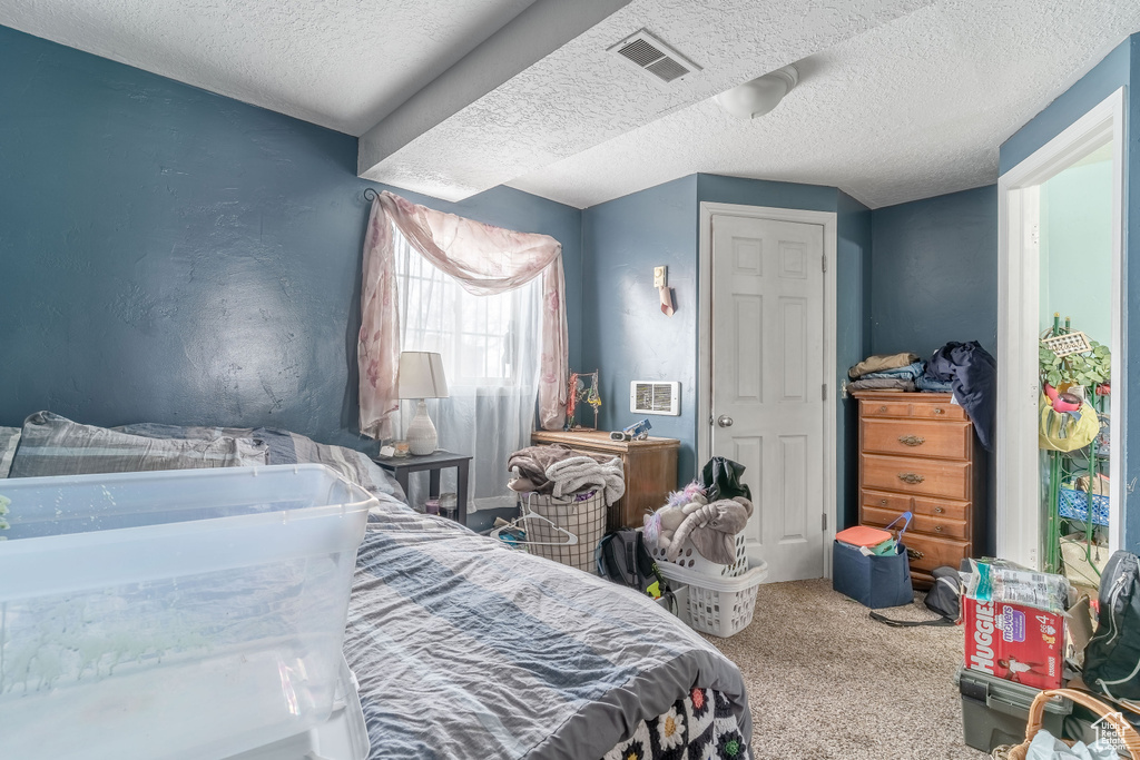Bedroom featuring a textured ceiling, carpet floors, and visible vents