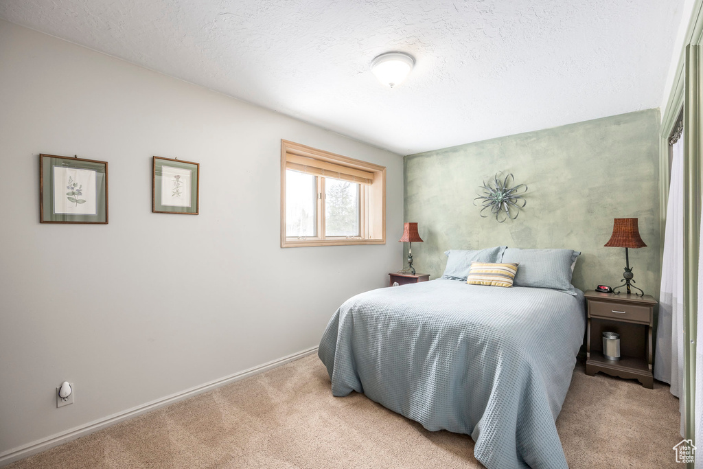 Carpeted bedroom featuring baseboards and a textured ceiling