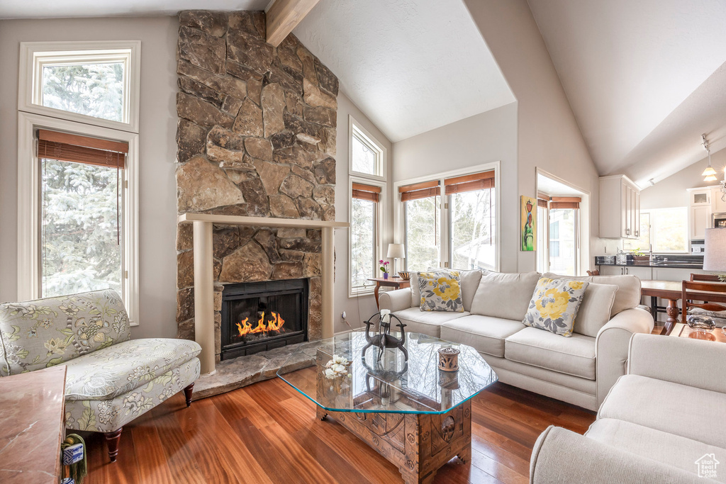 Living room with wood-type flooring, beam ceiling, a wealth of natural light, and a fireplace