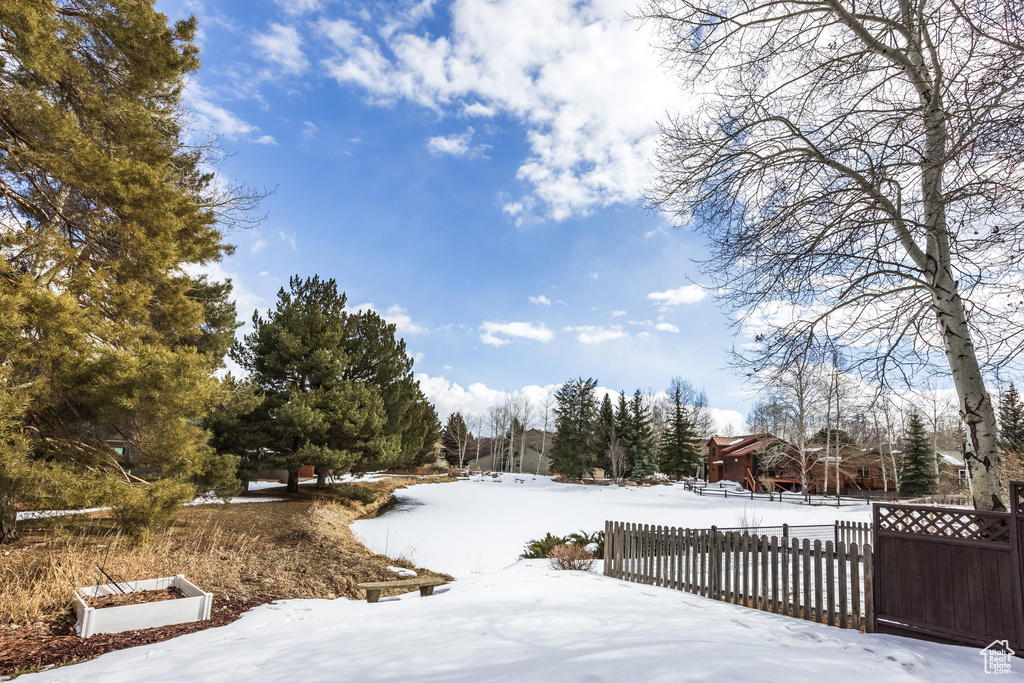Yard covered in snow featuring fence