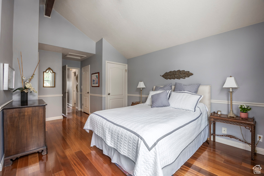 Bedroom featuring beam ceiling, high vaulted ceiling, baseboards, wood finished floors, and a closet