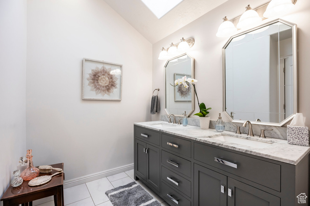 Bathroom featuring a sink, baseboards, vaulted ceiling, and double vanity