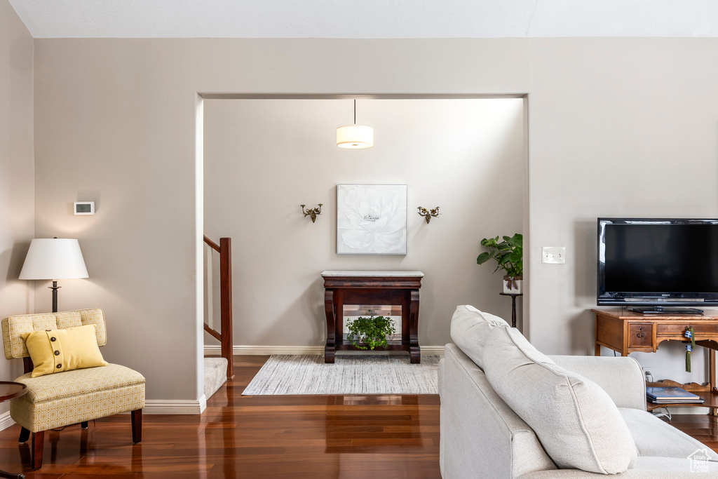 Living room featuring stairway, baseboards, and dark wood-style flooring
