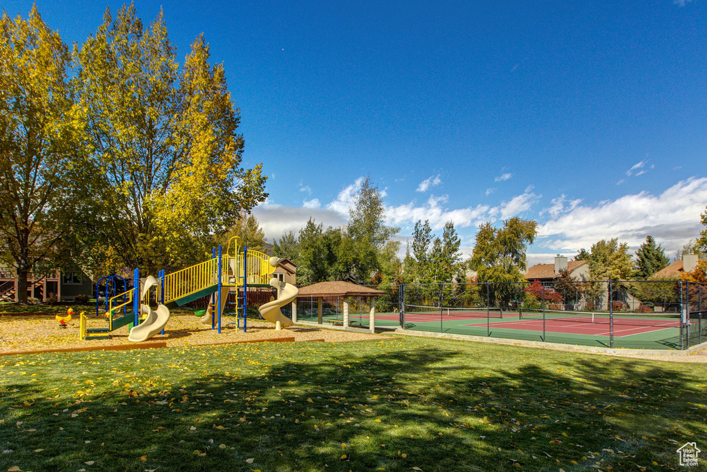 View of sport court with a lawn, fence, and playground community