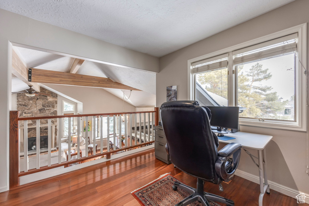 Office with vaulted ceiling with beams, baseboards, wood finished floors, and a textured ceiling
