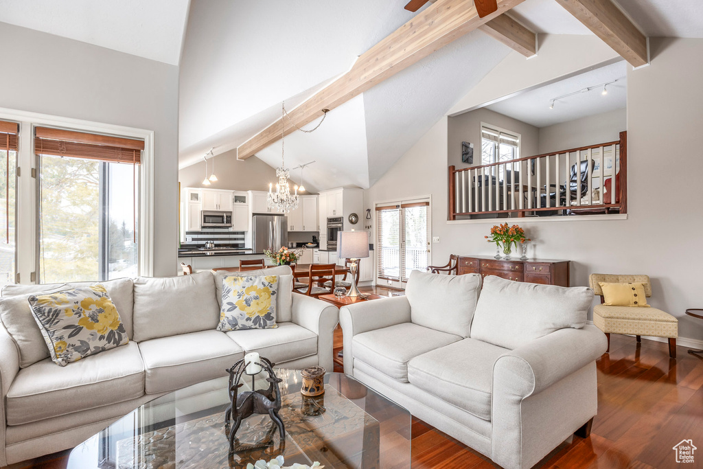 Living room with an inviting chandelier, beam ceiling, rail lighting, baseboards, and wood finished floors