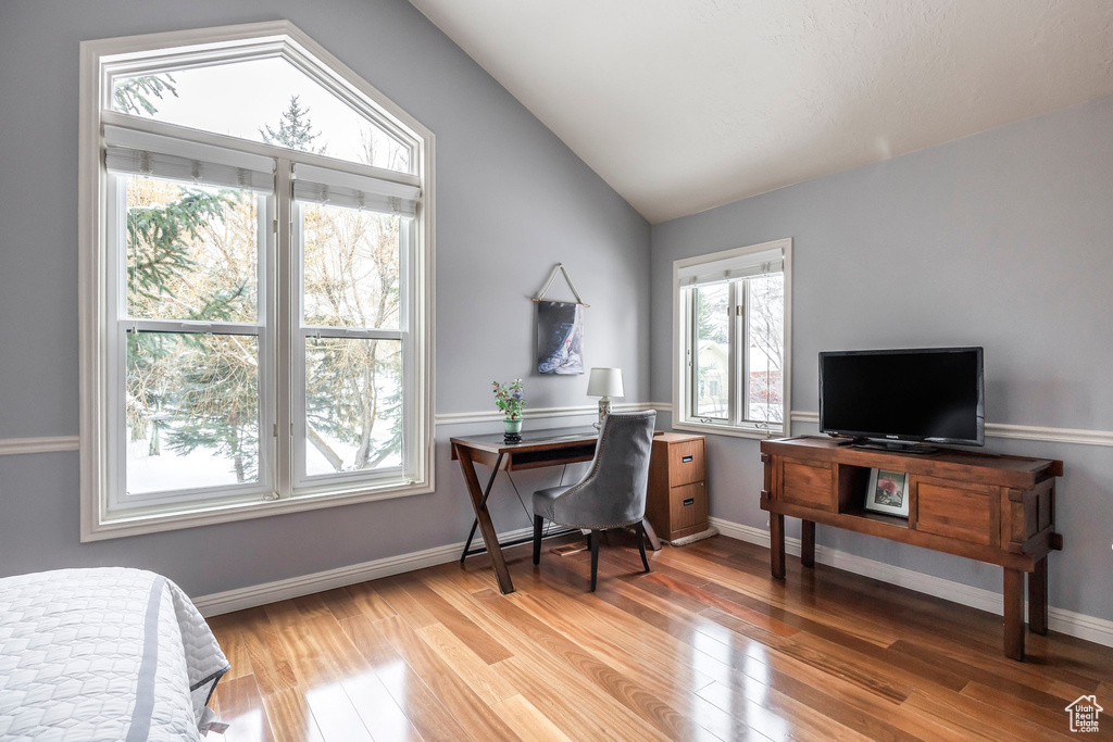 Office area with baseboards, vaulted ceiling, and light wood-type flooring