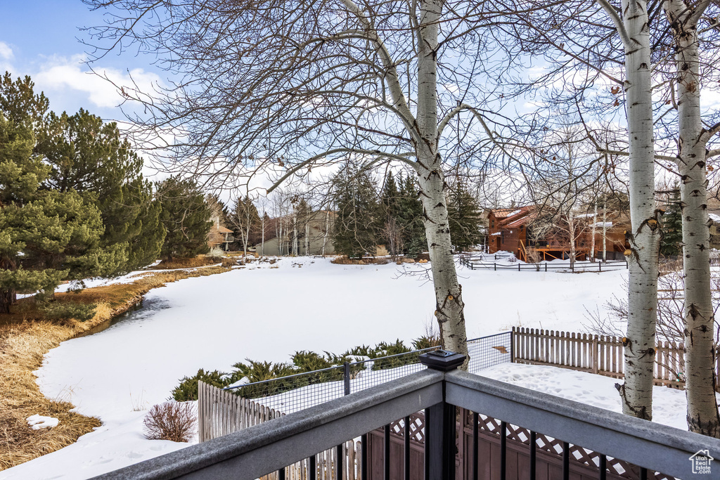 Yard covered in snow featuring fence and a balcony