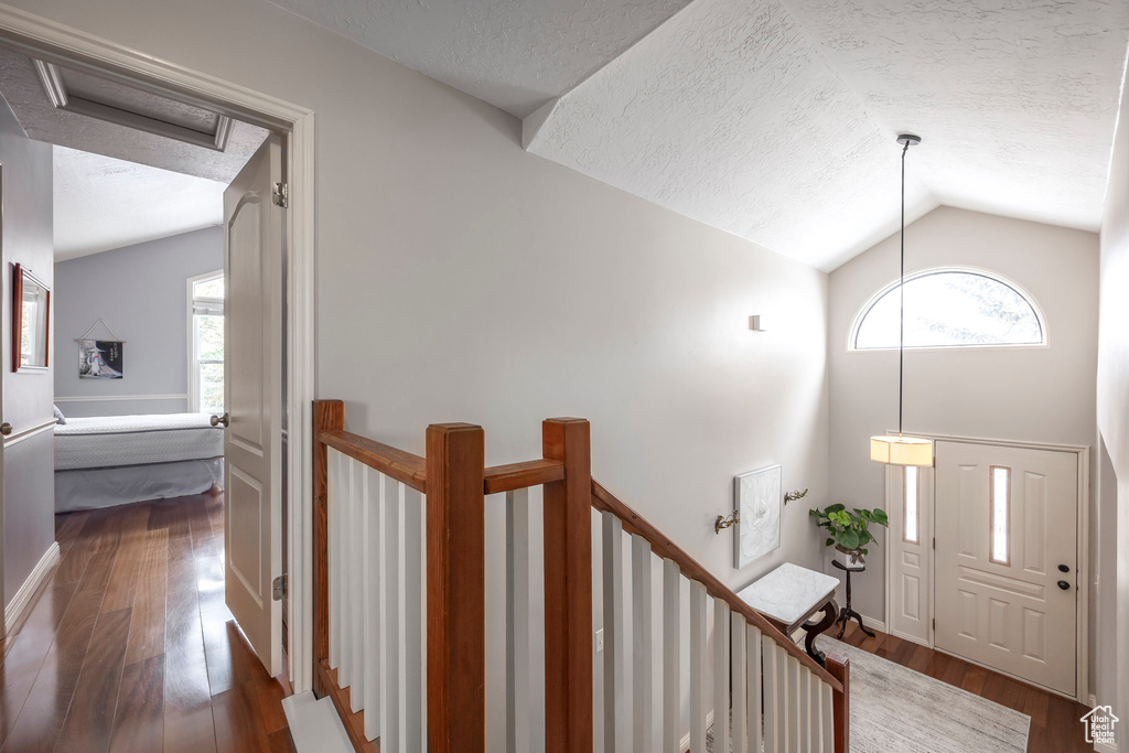 Entrance foyer with a textured ceiling, lofted ceiling, dark wood-style floors, and a wealth of natural light