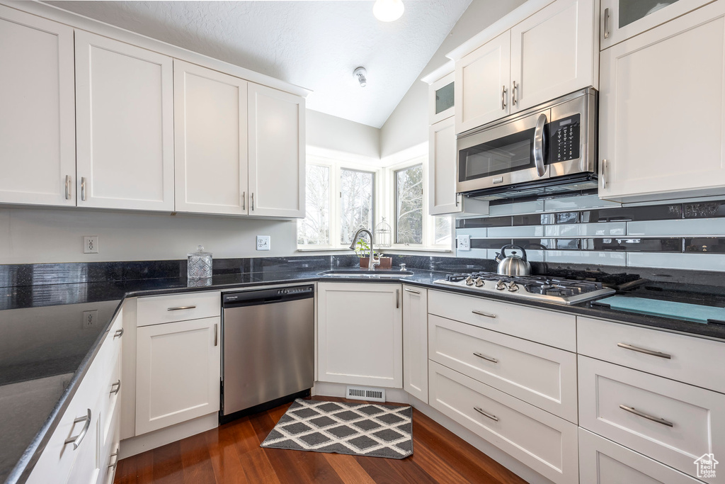 Kitchen with visible vents, appliances with stainless steel finishes, vaulted ceiling, a sink, and white cabinets