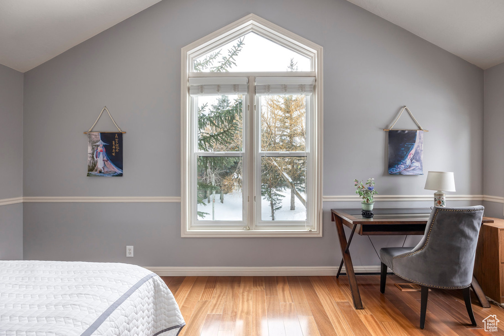 Bedroom featuring baseboards, wood finished floors, and lofted ceiling