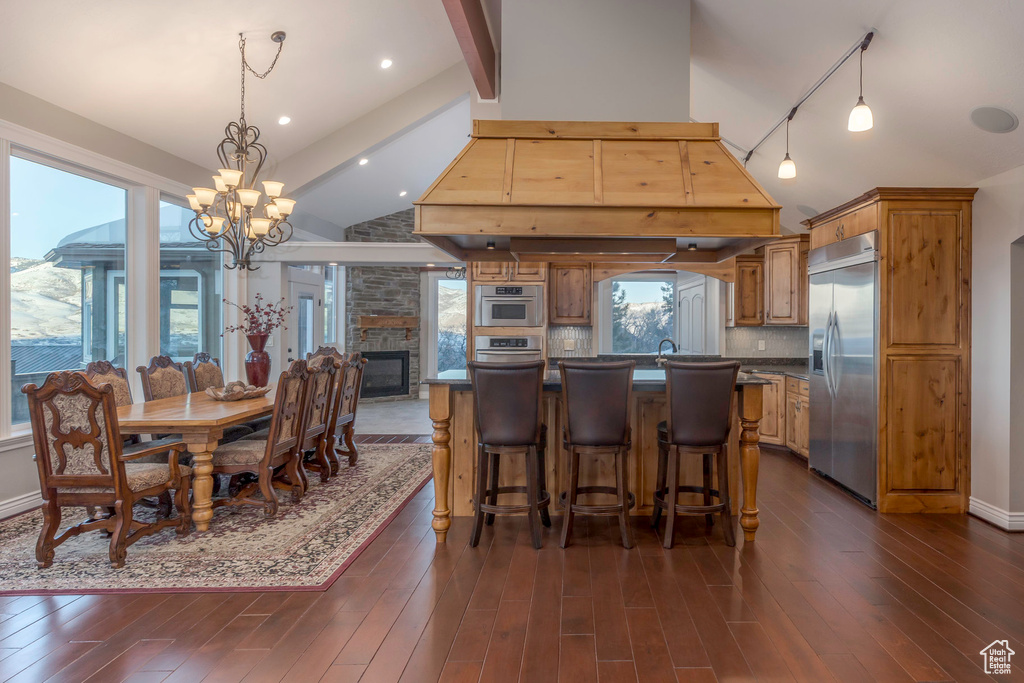 Dining area with a fireplace, a notable chandelier, rail lighting, and dark wood-type flooring