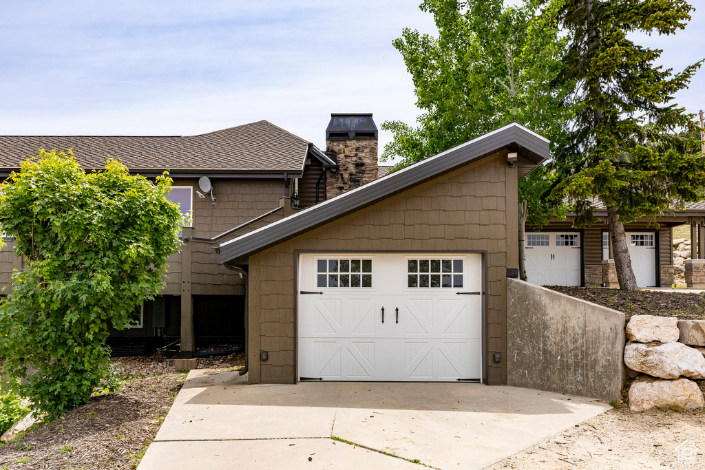 View of front facade with driveway and a chimney