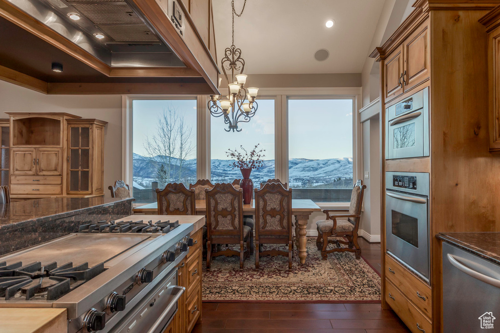 Kitchen with brown cabinetry, custom exhaust hood, a mountain view, and dishwasher