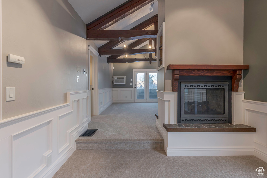 Unfurnished living room with a decorative wall, carpet, a multi sided fireplace, beamed ceiling, and visible vents