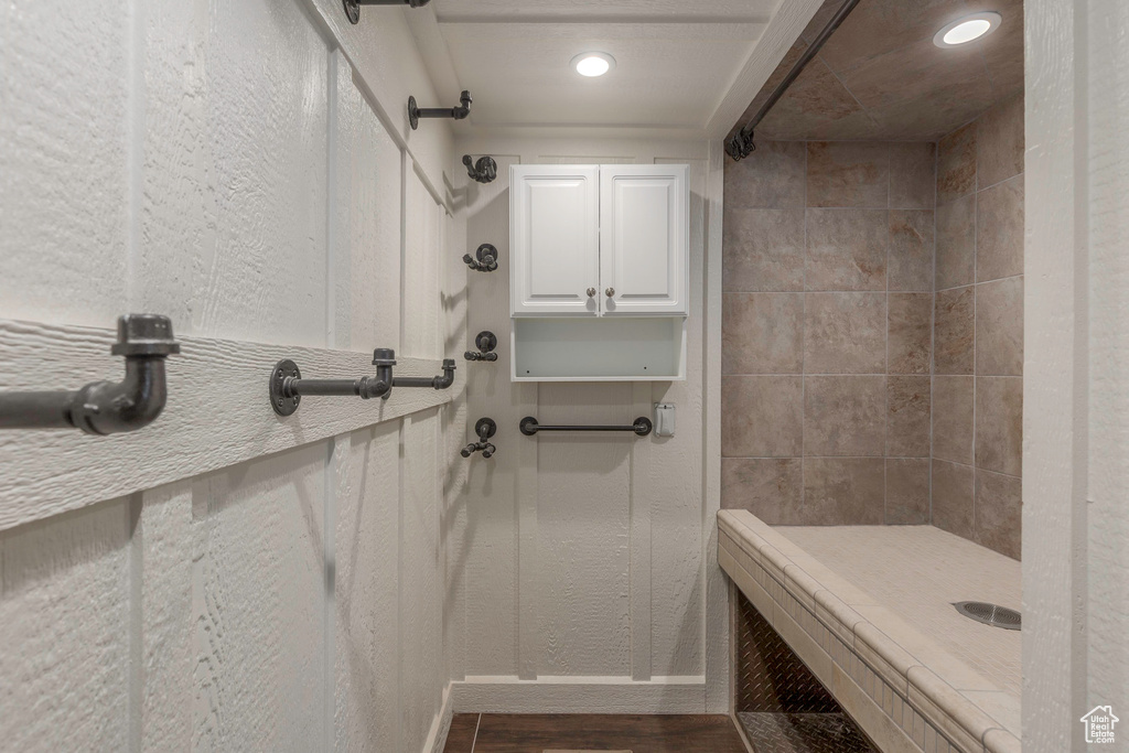 Bathroom featuring recessed lighting, baseboards, tiled shower, and wood finished floors