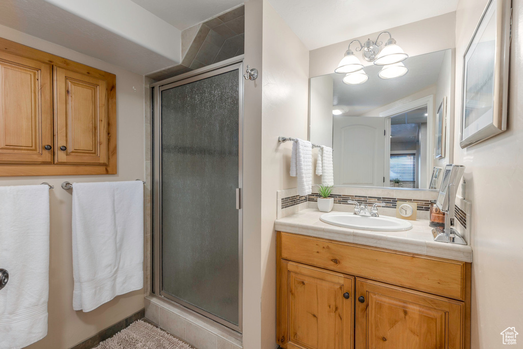 Full bathroom with vanity, a notable chandelier, tasteful backsplash, and a stall shower