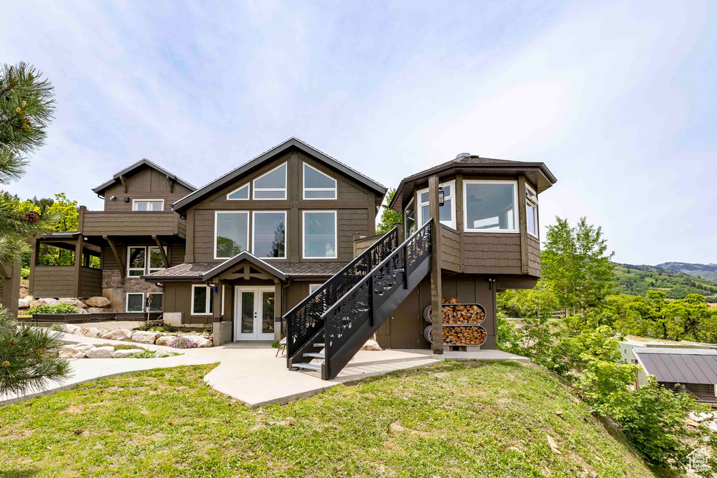 Back of property with french doors, a lawn, and stairway