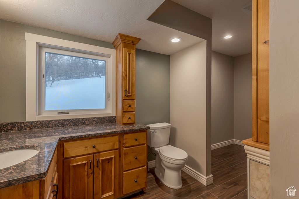 Bathroom with vanity, wood finished floors, toilet, baseboards, and recessed lighting