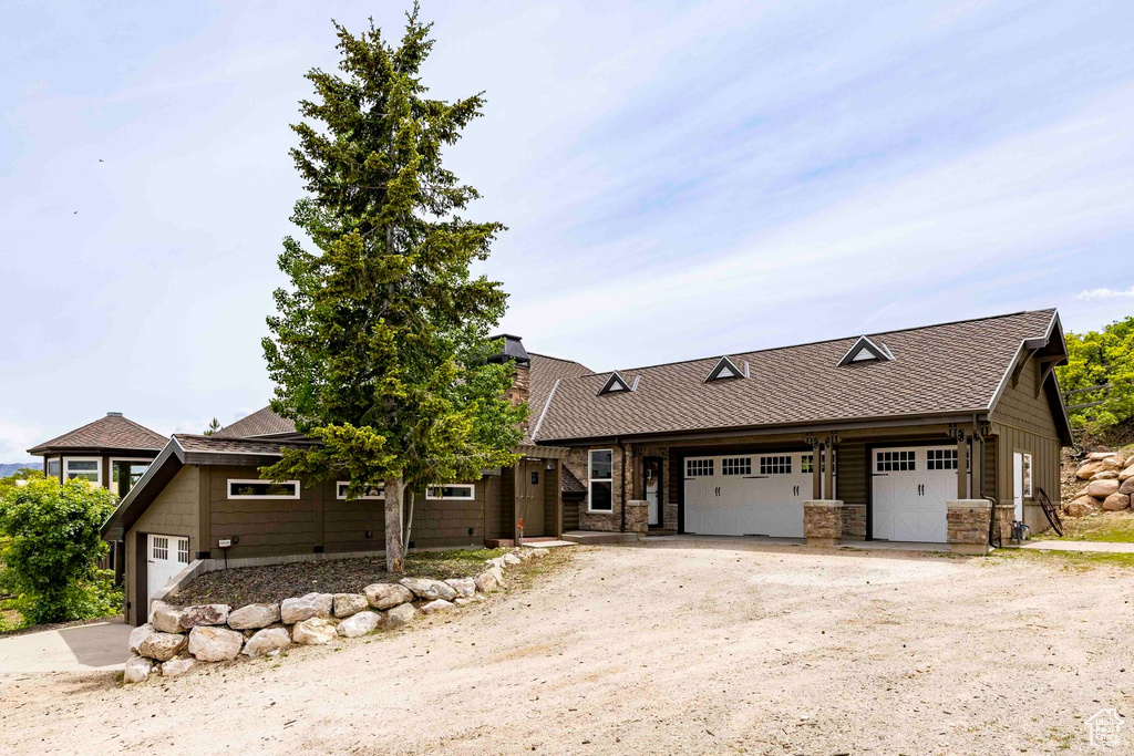 View of front facade with dirt driveway, an attached garage, and a chimney