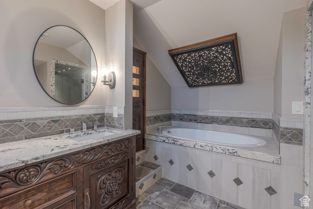 Bathroom with lofted ceiling, a garden tub, and vanity