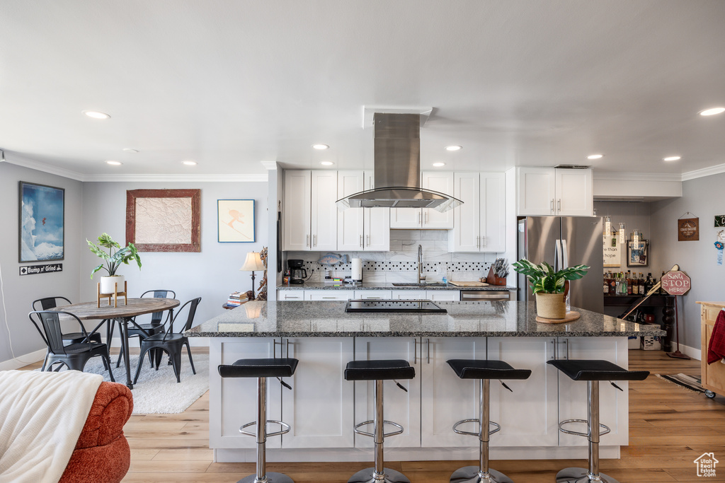 Kitchen with island exhaust hood, freestanding refrigerator, baseboards, ornamental molding, and backsplash