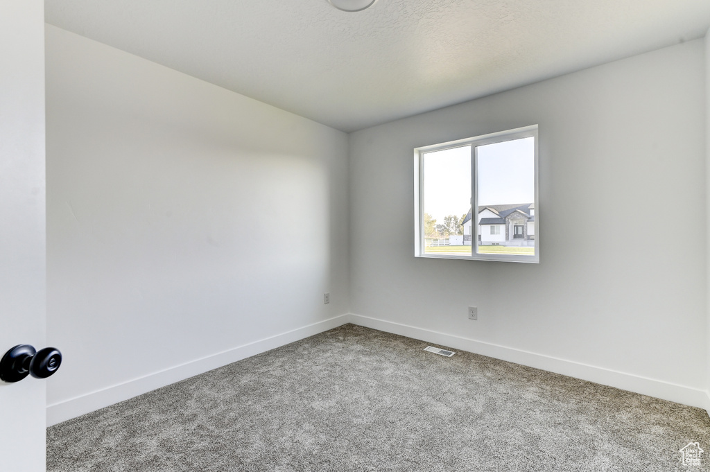 Carpeted spare room with visible vents and baseboards