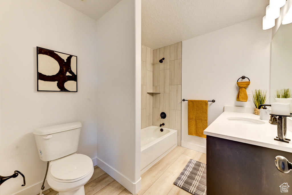 Bathroom with toilet, shower / bath combination, wood finished floors, vanity, and baseboards