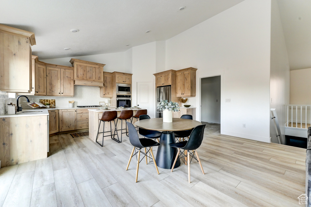 Kitchen with a breakfast bar area, a sink, light countertops, appliances with stainless steel finishes, and a center island