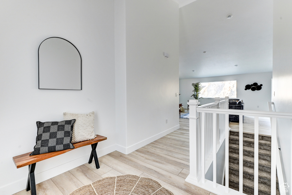 Hall with baseboards, an upstairs landing, and wood finished floors