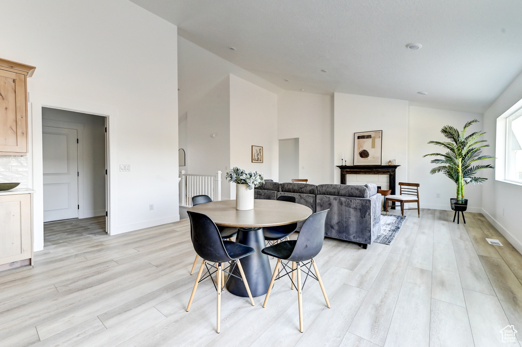 Dining area featuring baseboards, high vaulted ceiling, and light wood-style floors