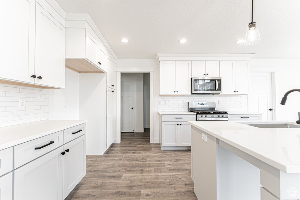 Kitchen featuring appliances with stainless steel finishes, a sink, white cabinetry, recessed lighting, and light wood-style floors
