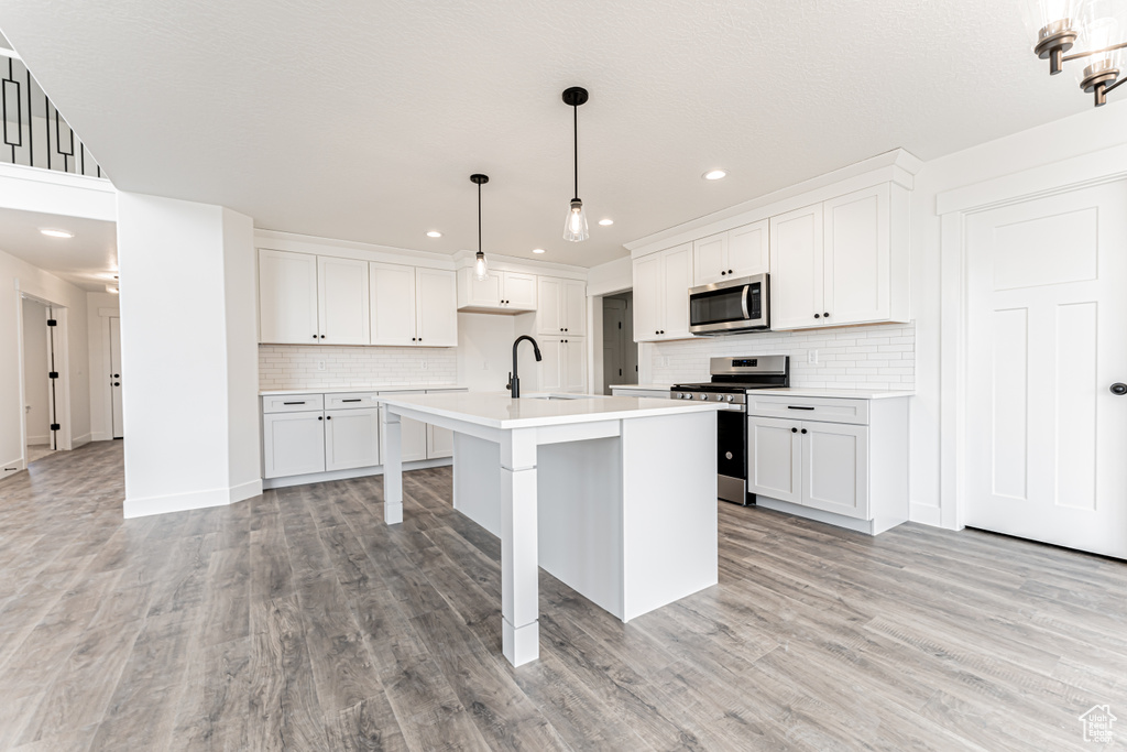 Kitchen featuring appliances with stainless steel finishes, a sink, recessed lighting, backsplash, and light countertops