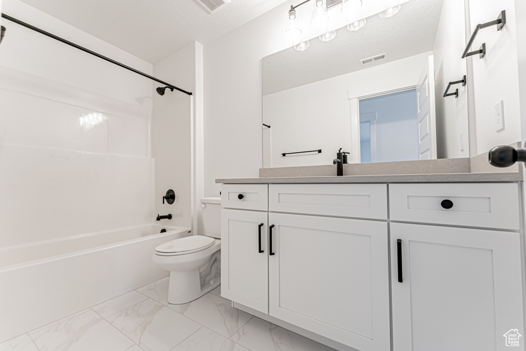 Bathroom with toilet, vanity, shower / tub combination, marble finish flooring, and a textured ceiling