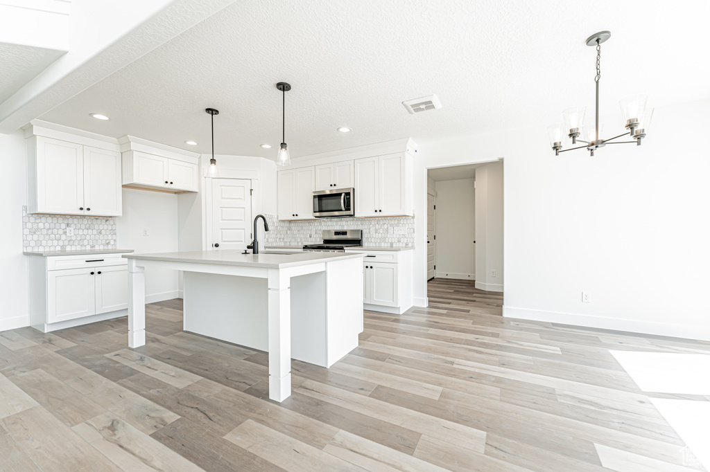 Kitchen with appliances with stainless steel finishes, a sink, tasteful backsplash, a chandelier, and recessed lighting