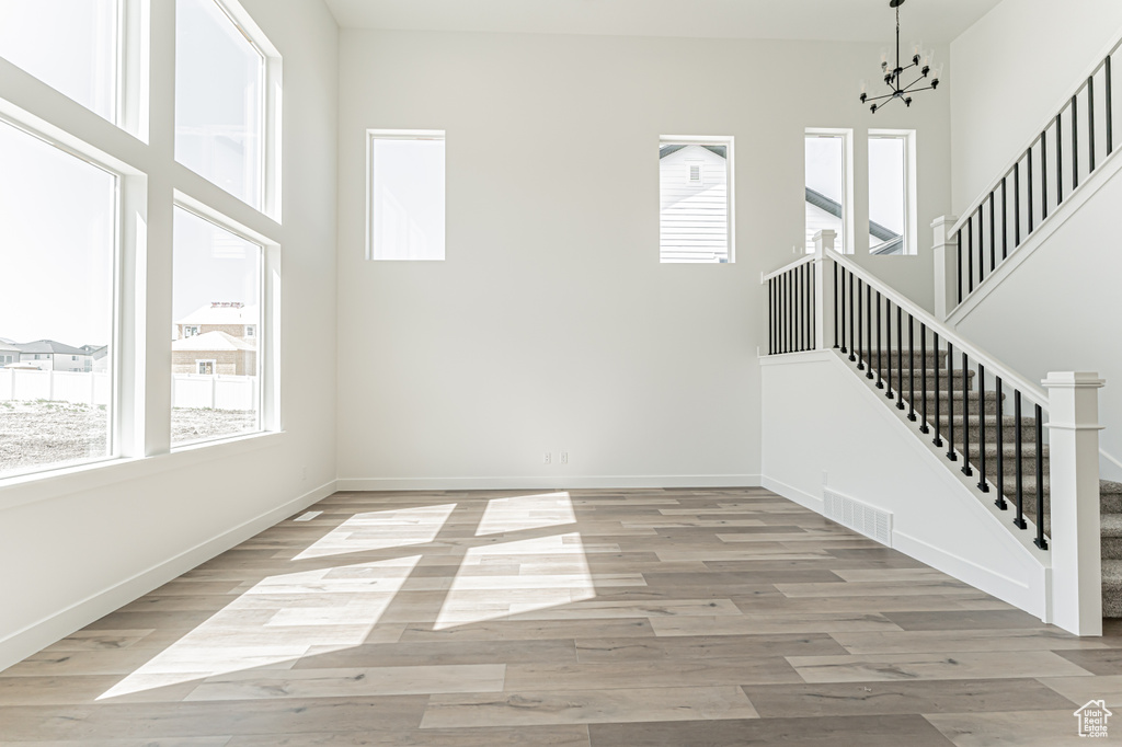Unfurnished room with plenty of natural light, stairs, baseboards, and light wood-type flooring