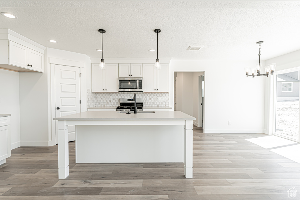 Kitchen featuring appliances with stainless steel finishes, a sink, backsplash, recessed lighting, and a chandelier