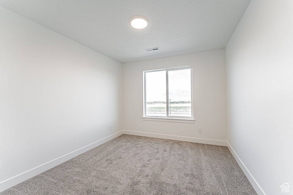 Empty room featuring light carpet and baseboards