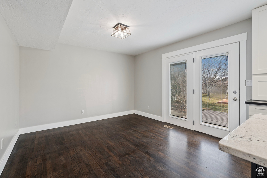 Unfurnished dining area with dark wood-style floors and baseboards