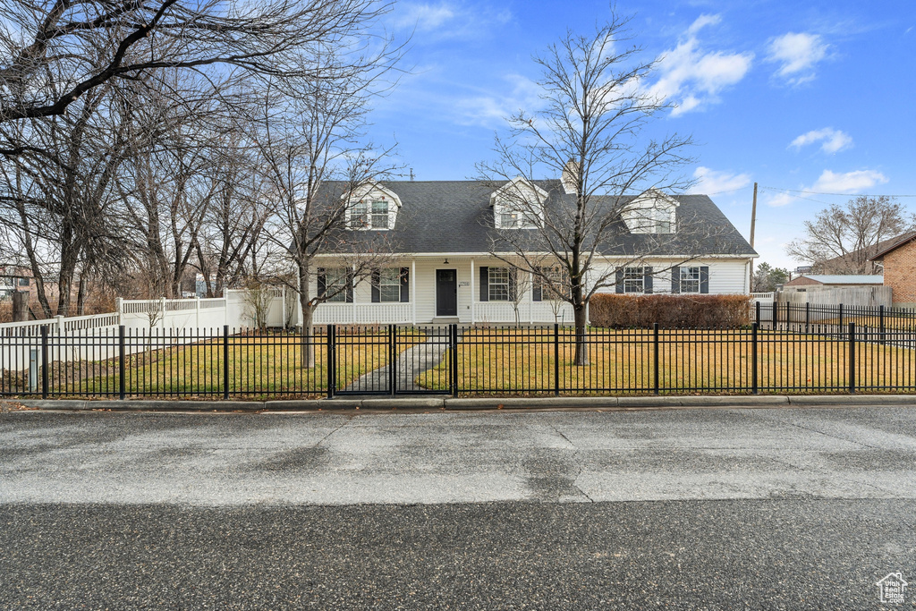 Cape cod home featuring a fenced front yard and a front lawn