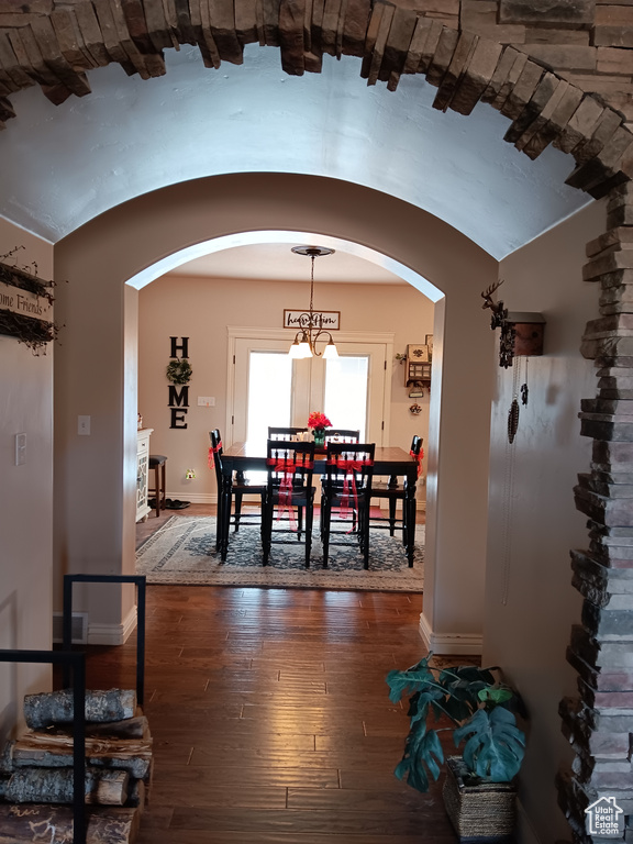 Dining area featuring hardwood / wood-style flooring, baseboards, arched walkways, and vaulted ceiling