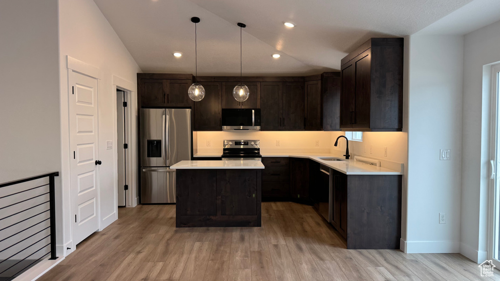 Kitchen with light countertops, appliances with stainless steel finishes, a sink, and light wood finished floors