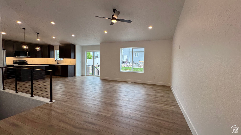 Unfurnished living room featuring baseboards, a ceiling fan, recessed lighting, and wood finished floors