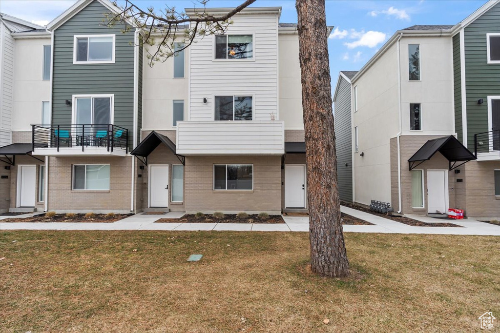 Townhome / multi-family property featuring brick siding and a front yard