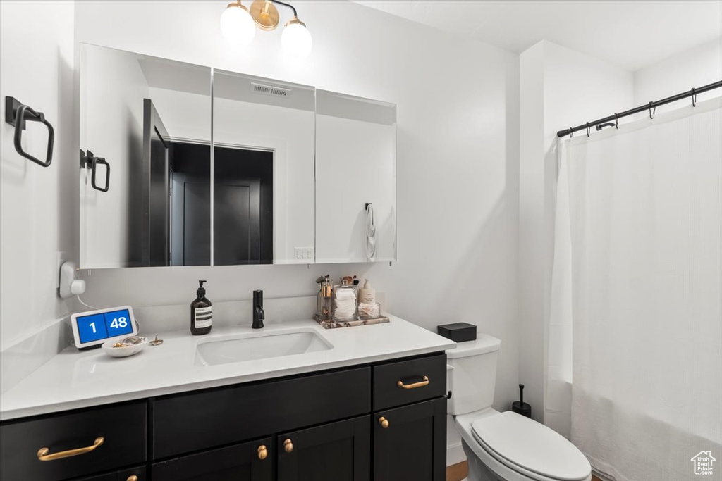 Full bathroom with toilet, visible vents, a shower with shower curtain, and vanity