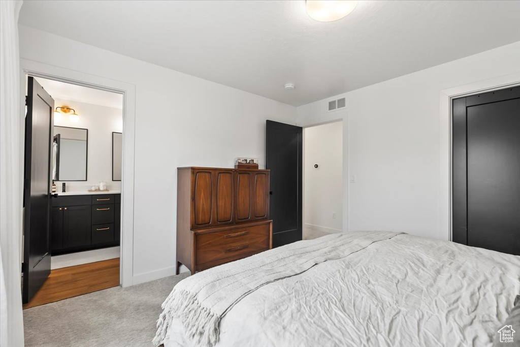 Bedroom with baseboards, ensuite bath, visible vents, and light colored carpet