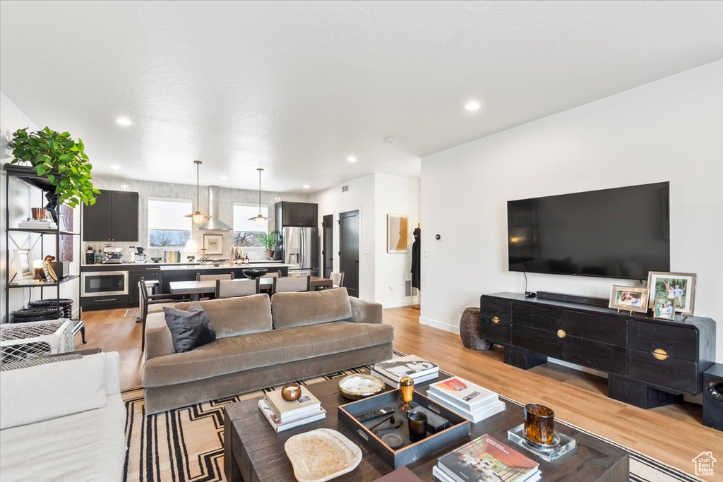 Living area with light wood-style floors, baseboards, and recessed lighting